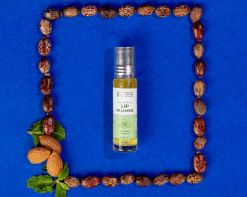 A clear bottle of PNKT Natural Lip Plummer with a white label, placed in the center of a grid of almonds and leaves on a blue background.